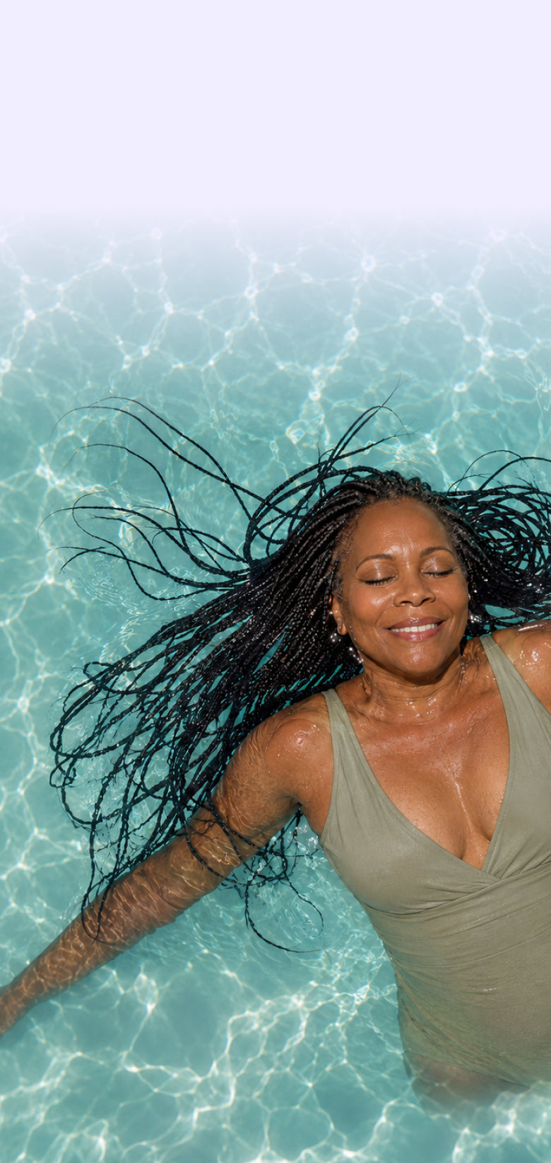 Angie floating in a pool with long jet black braids