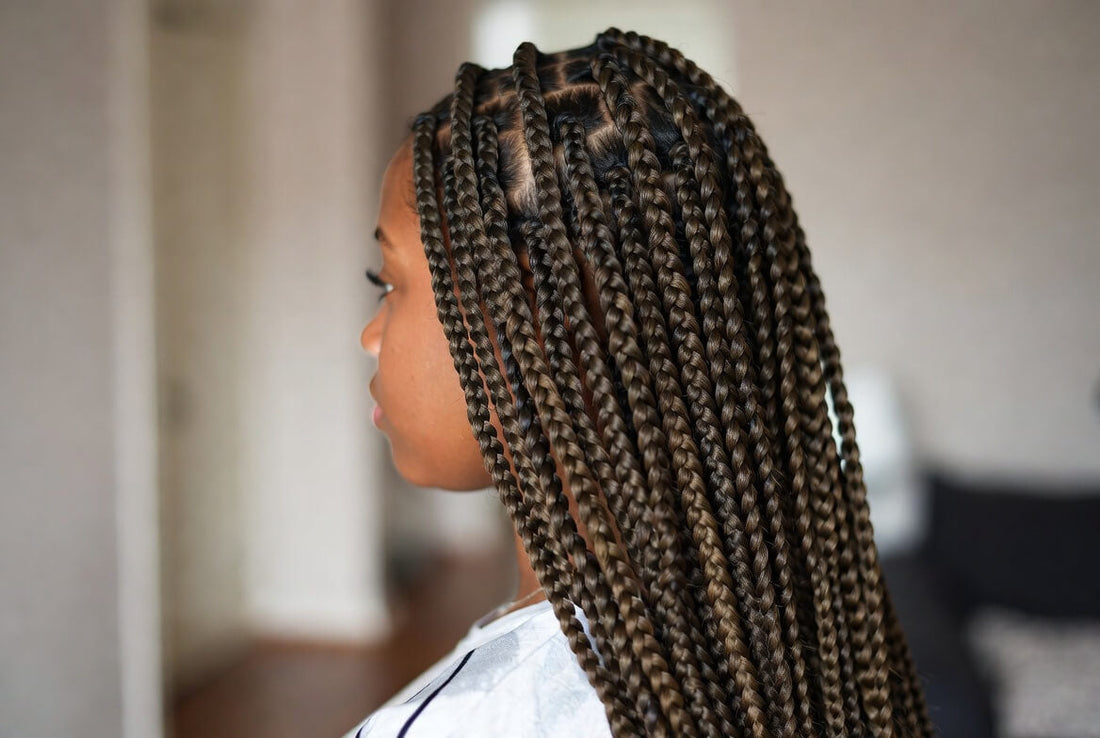 Side profile of a young Black girl with clean, medium-length knotless box braids without chemical treatment.