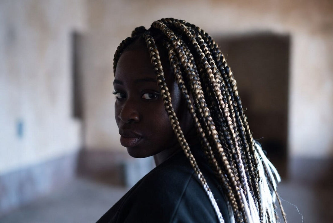 Stylish Black woman with long black and blonde synthetic box braids looking over her shoulder.