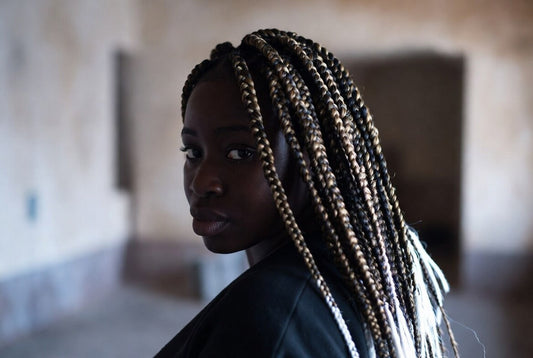 Stylish Black woman with long black and blonde synthetic box braids looking over her shoulder.